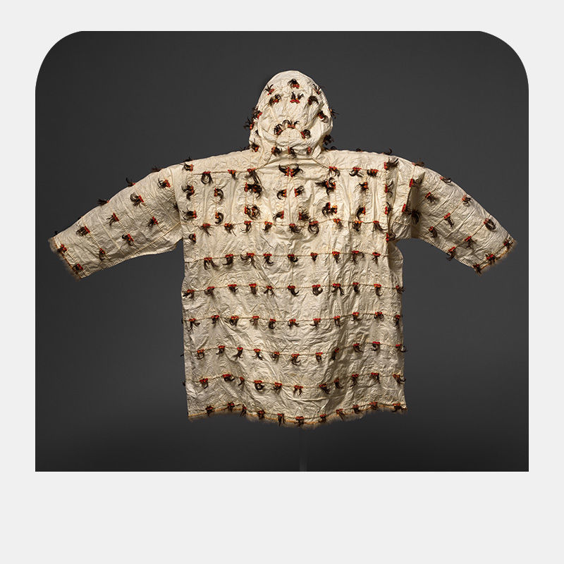 A parchment hued parka lined with thin red lines and dotted with brown material.